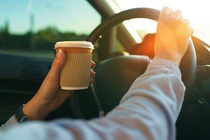 Woman with coffee to go driving her car